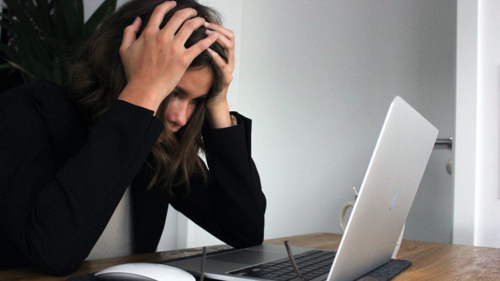 Frustrated woman holding her head in front of a notebook